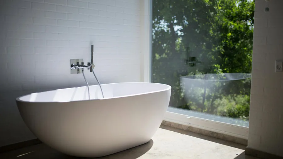 Freestanding oval tub set against a floor-to-ceiling window