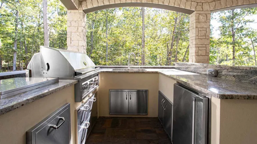 Covered outdoor kitchen with a stainless grill and granite counters