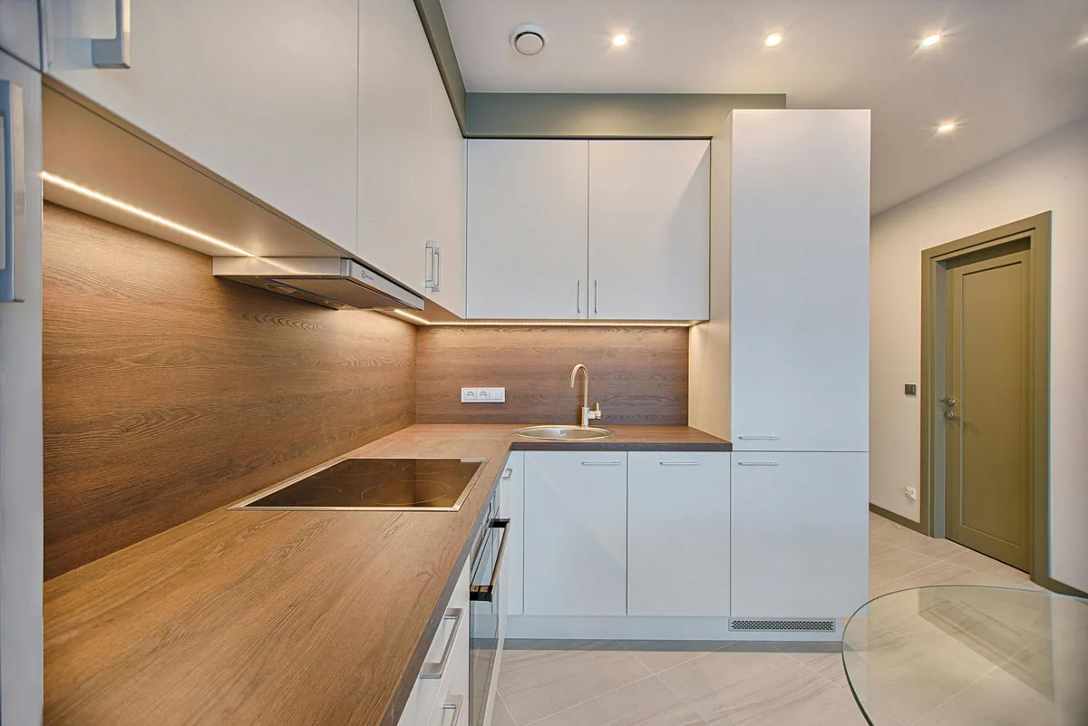 Galley kitchen with white cabinets and a timber worktop