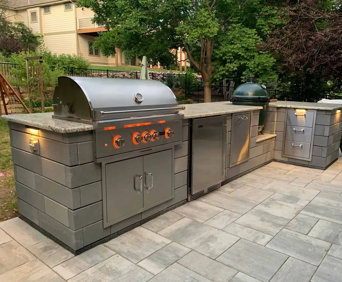Outdoor kitchen island with a stainless grill and paver patio
