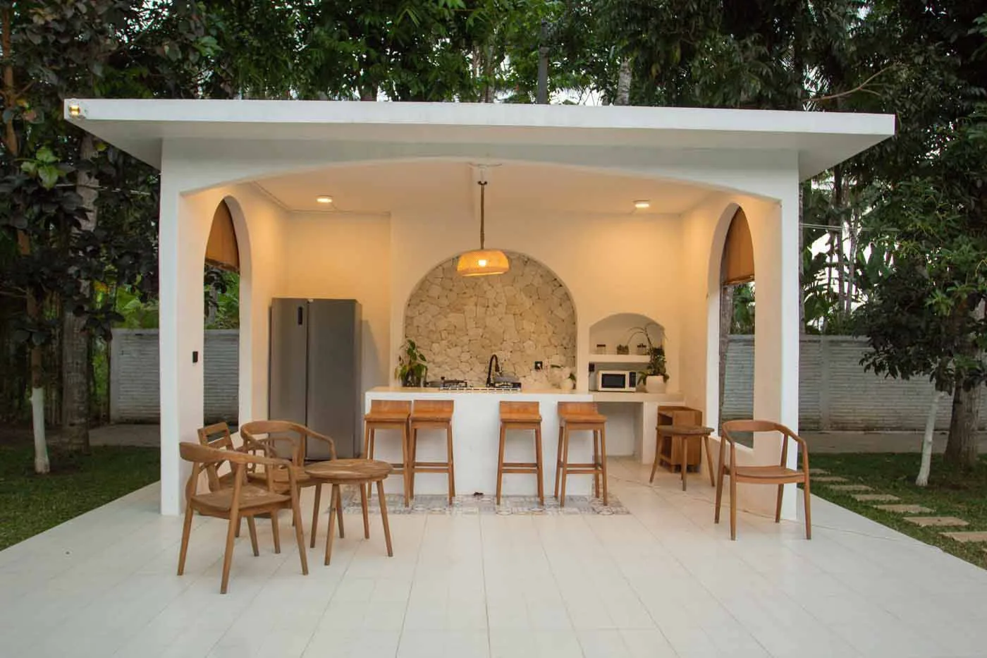 Outdoor kitchen pavilion with an island bar and stone back wall