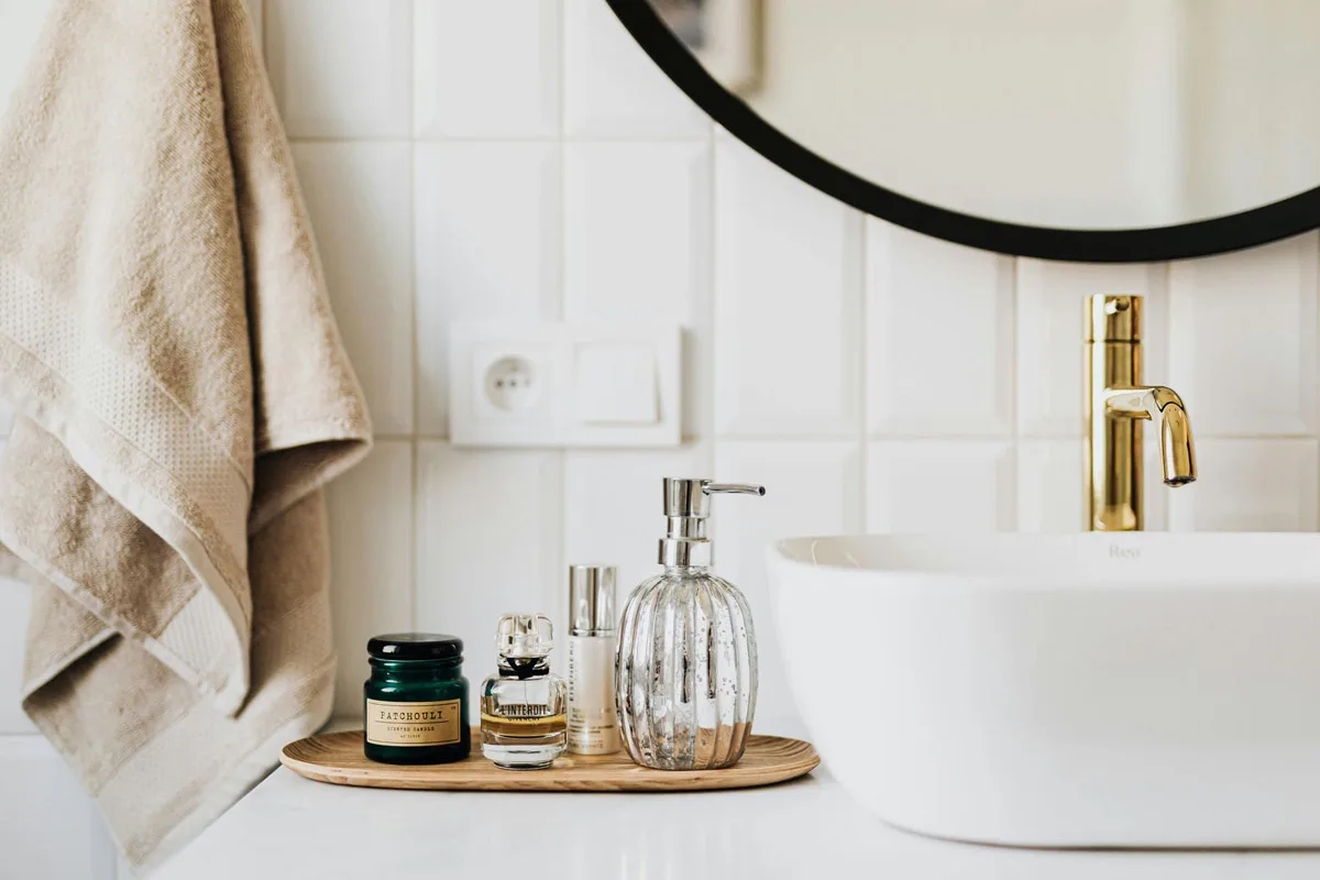 Vanity detail with a round black-framed mirror, vessel basin and gold tap