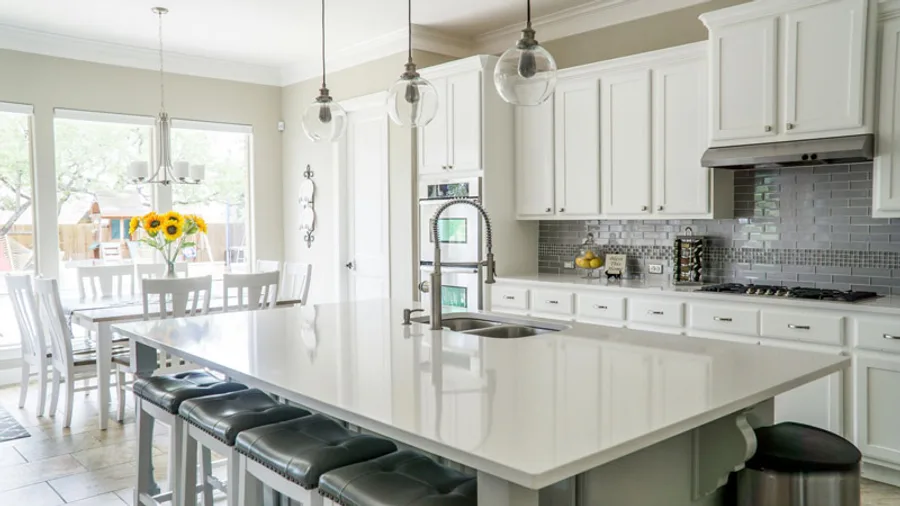 White shaker kitchen with a large quartz island and glass globe pendants